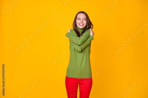 Portrait of lovely glad dreamy cheerful girl hugging herself congrats isolated over bright yellow color background © deagreez