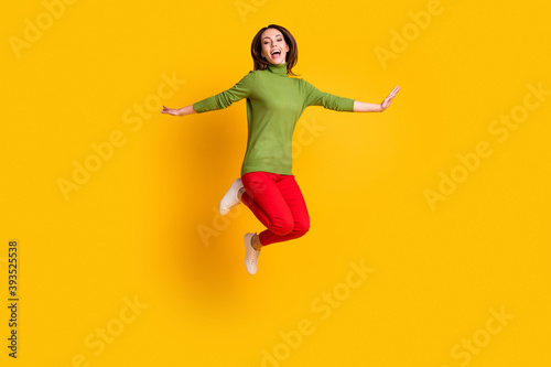Full body photo of crazy lady jump up spread arms wear casual pullover sneakers trousers isolated yellow color background