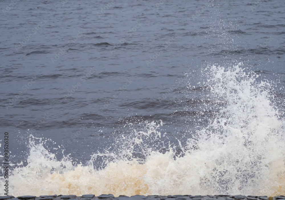 Waves crash on the embankment parapet, water splashes Waves crash on the embankment parapet, water splashes