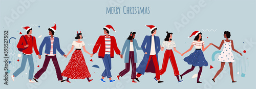 Happy people hold hands and celebrate Christmas and New Year. Joyful men and women in santa hats at a corporate party
