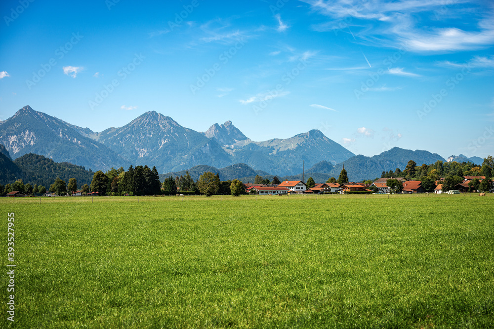 Green Agricultural Fields and Bavarian Alps with the small town of Schwangau near Fussen, Ostallgau, Bavaria, Germany.