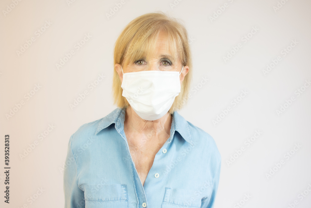 Senior woman in medical mask isolated on yellow background looking at camera protecting from flu epidemic and pollution - coronavirus pandemic, prevention, protection concept Senior woman in medical mask isolated on yellow background looking at camera protecting from flu epidemic and pollution - coronavirus pandemic, prevention, protection concept
