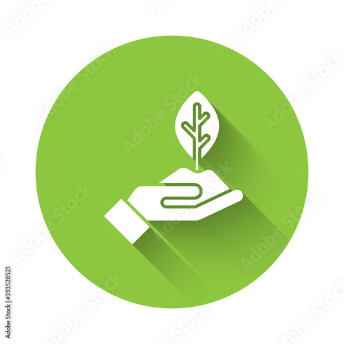 White Plant in hand of environmental protection icon isolated with long shadow. Seed and seedling. Planting sapling. Ecology concept. Green circle button. Vector.