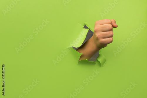 Kid's fist through broken green paper