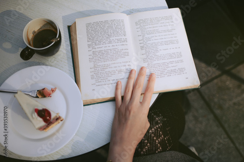 Canvas Print Overhead detail of a woman with reading a book in a cafe