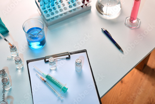 Syringe and vials on notepad on table in laboratory top