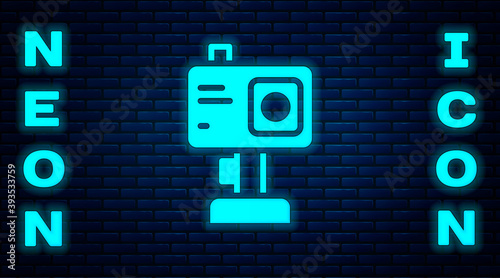 Glowing neon Action extreme camera icon isolated on brick wall background. Video camera equipment for filming extreme sports. Vector.