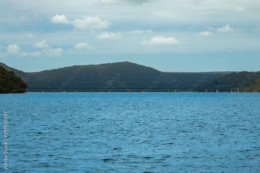 Steel Railway Bridge on Hawkesbury River on Sydney Central Coast NSW Australia with green lush mountains in background