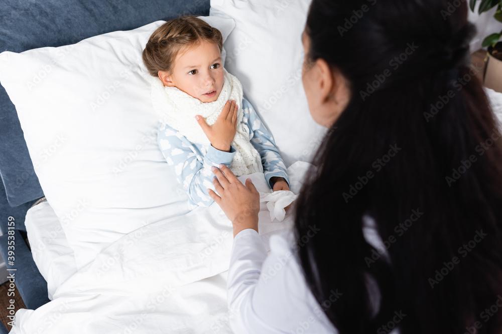 high angle view of doctor touching diseased girl lying in bed at home