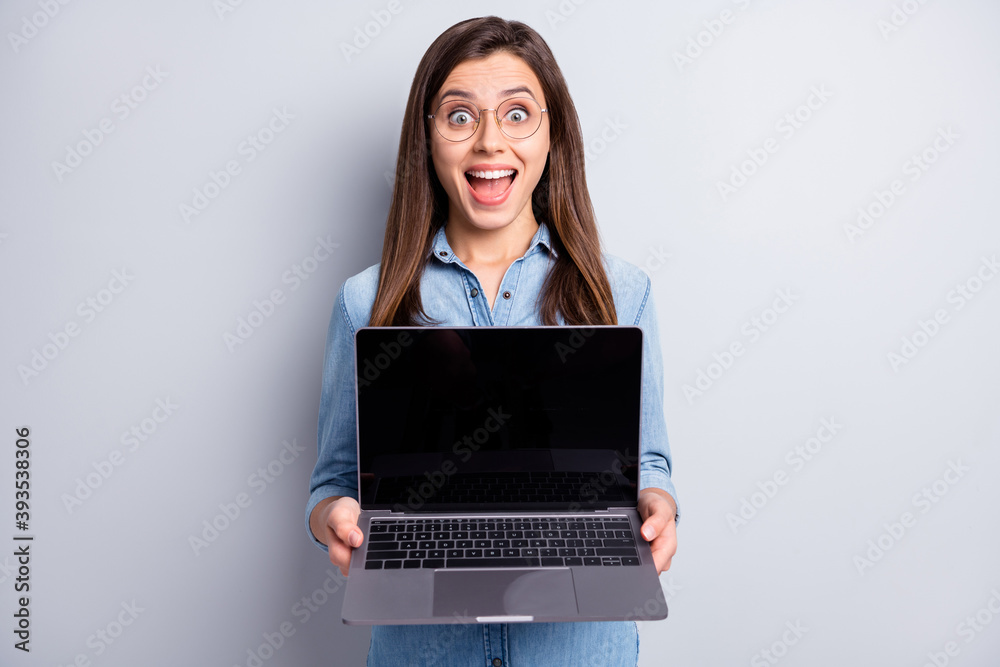 Photo of amazed charming young woman show hold laptop screen copyspace amazed shocked isolated on grey color background Photo of amazed charming young woman show hold laptop screen copyspace amazed shocked isolated on grey color background