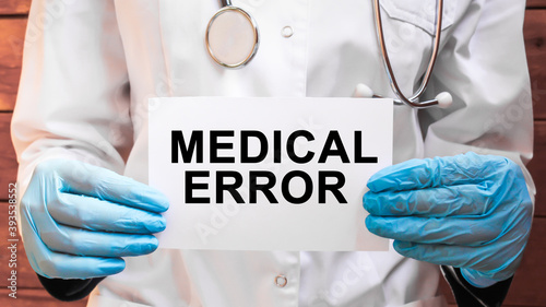The doctor's blue - gloved hands show the word MEDICAL ERROR - . a gloved hand on a white background. Medical concept. the medicine