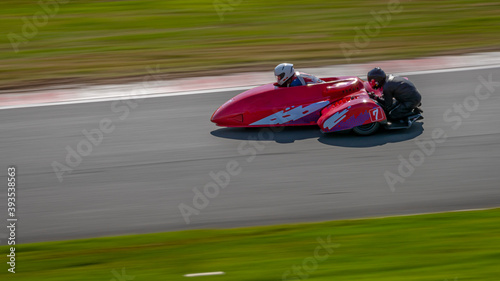 A panning shot of a racing sidecar as it corners on a track.