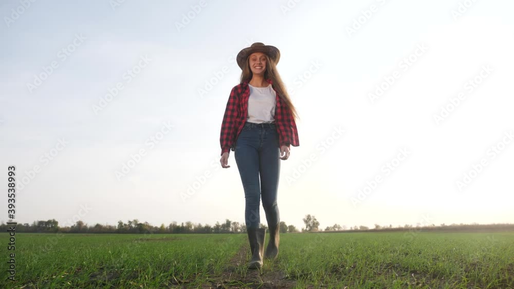 agriculture. girl farmer in rubber boots walk country road near a green field of wheat grass. farmer worker go home after harvesting end of the working day feet in rubber boots crop. agriculture
