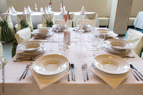 Wedding table in restaurant interior prepared for the guest.Beautiful decorated with plates , candles and glasses,