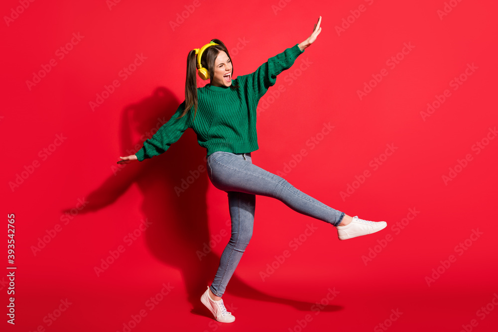 Full size photo of young excited crazy cheerful woman listen music yellow earphones hold hands balance isolated on red color background