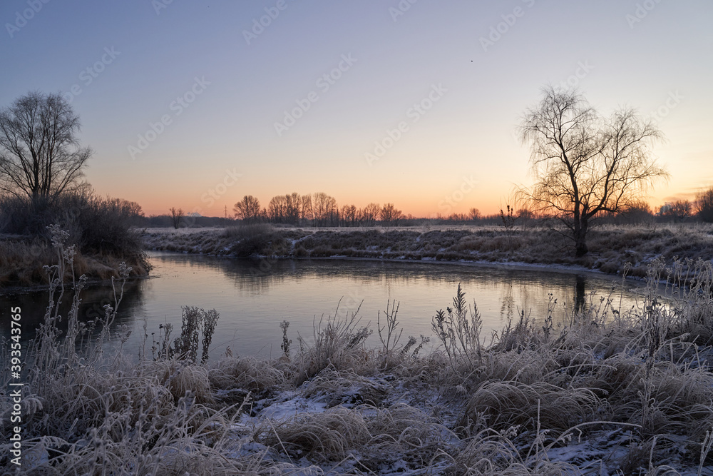 Breath of winter, first ice on the lake, dawn on a frosty morning with frost on the grass, close-up of frost, patterns on the first ice.