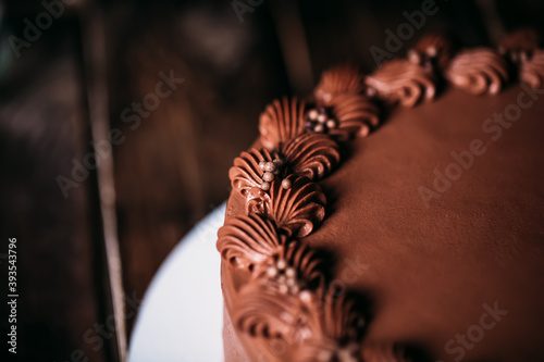 Close-up of a chocolate cake with beautiful patterns of chocolate cream. Traditional sweets for birthday and other holidays