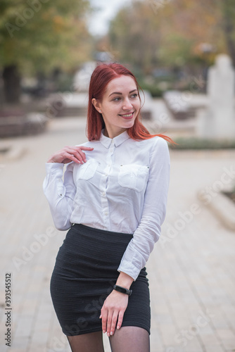 Beautiful and cute red-haired girl with pleasure posing on the street