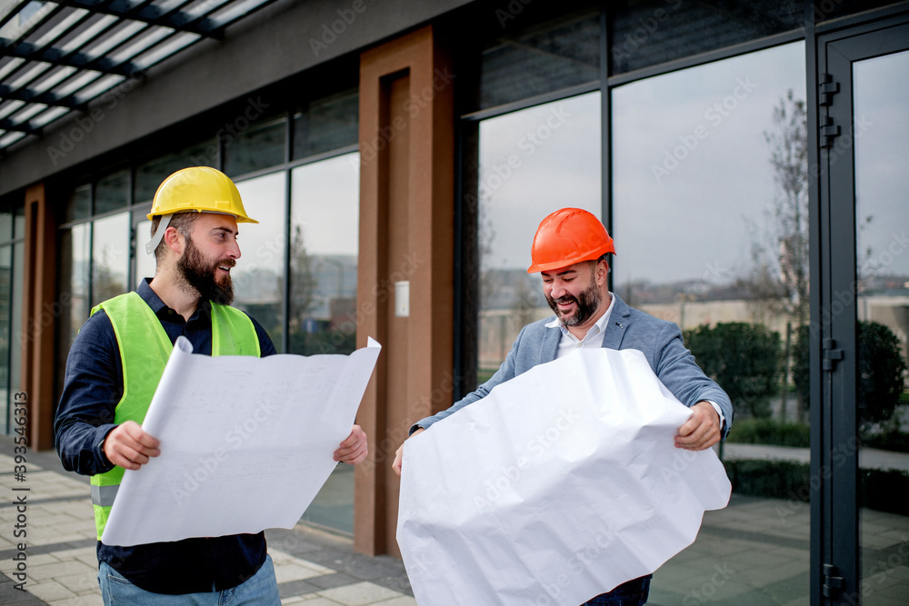 Two architects examining a blueprint and working on a building project. Two architects examining a blueprint and working on a building project.