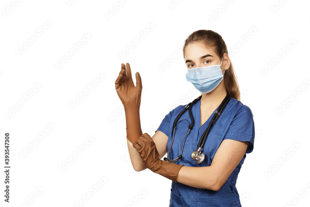 Young female doctor in blue coat getting ready for work putting on protective brown surgical gloves isolated on white background. Young female doctor in blue coat getting ready for work putting on protective brown surgical gloves isolated on white background.
