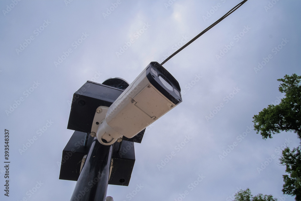 Security camera hanging among wire in guarded bridge with cloudy sky background. Security camera hanging among wire in guarded bridge with cloudy sky background.