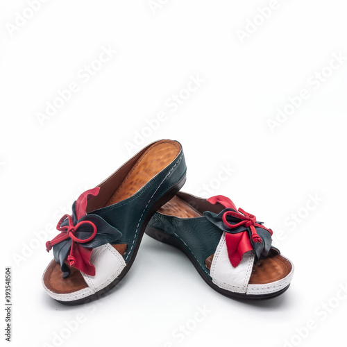 Women's summer shoes on a white background. Genuine leather mules with thick soles. Red-white-blue colors. Decorated with a flower and a bow. Isolated.