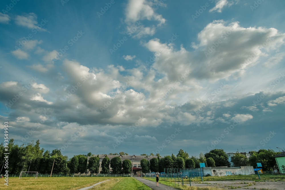 thick cloudy blue sky above the school yard and shady trees green thick cloudy blue sky above the school yard and shady trees green