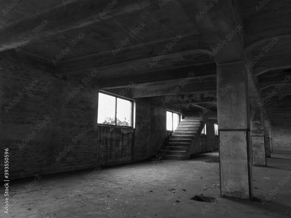 Interior of an empty deserted messy industrial warehouse, urban exploration of an abandoned building with broken windows and large pillars