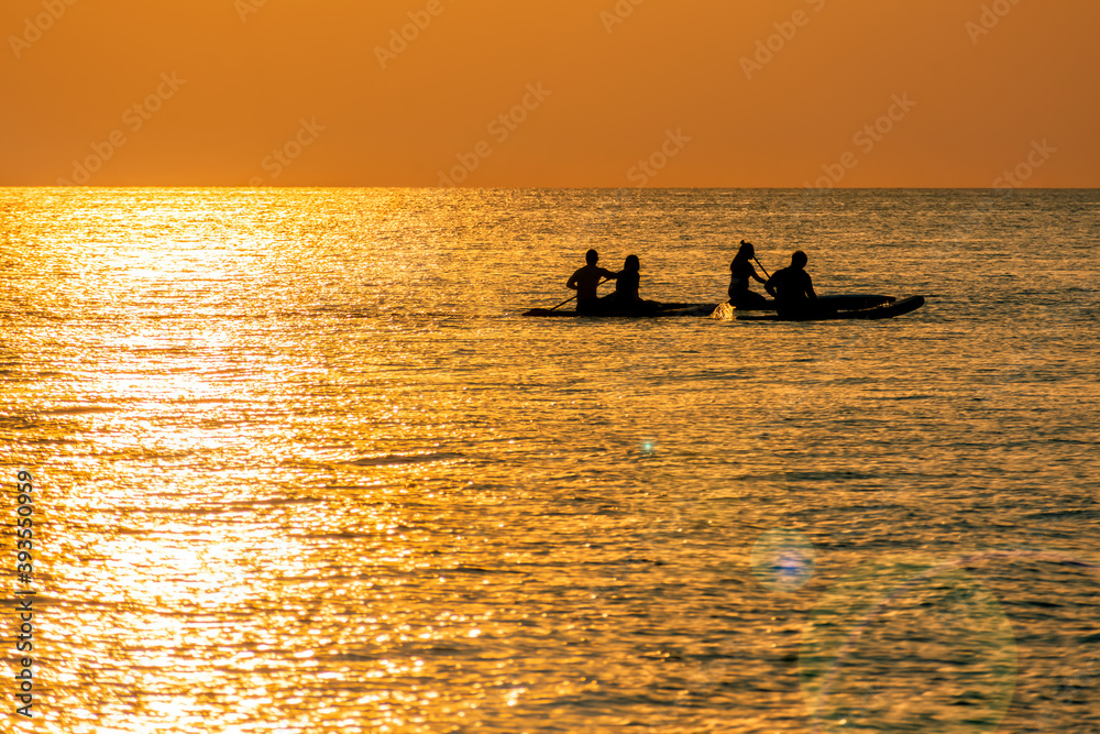 Couples Enjoy Golder Sunset while Kayaking out on the Sea.