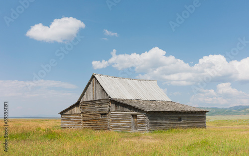 Early settler homestead isolated in the vast prairie and blue sky. Jackson, USA.