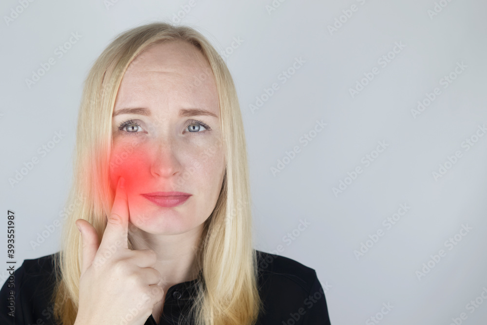 A woman clings to his cheek and winces in pain in his tooth. The concept of dental problems, caries, tooth decay, flux. White background and place for text. On examination by a doctor.