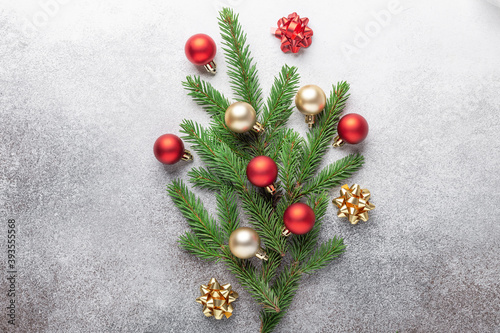 Minimal christmas composition. Bouquet of fir tree branches with red and gold christmas balls on stone background