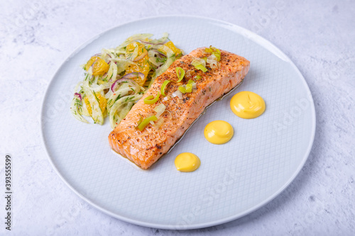 Fried salmon with fennel and orange salad with hollandaise sauce. Garnished with leeks. French dish. Close-up.