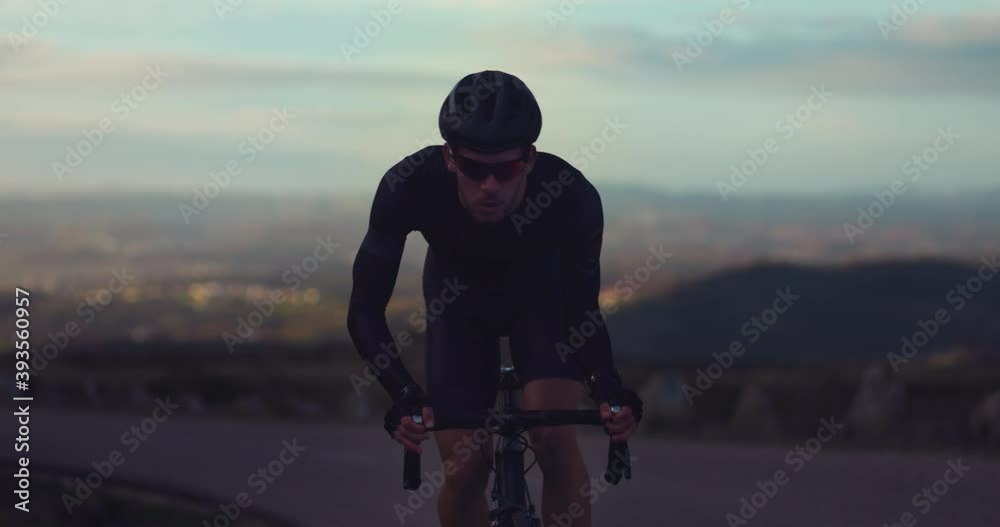 Professional cyclist riding bicycle on top of mountain at sunrise