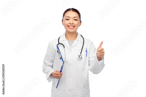 medicine  profession and healthcare concept - happy smiling asian female doctor in white coat with clipboard showing thumbs up