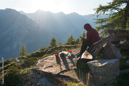 A woman checking her smartphone from her bivouac during a beautiful morning in the mountains.