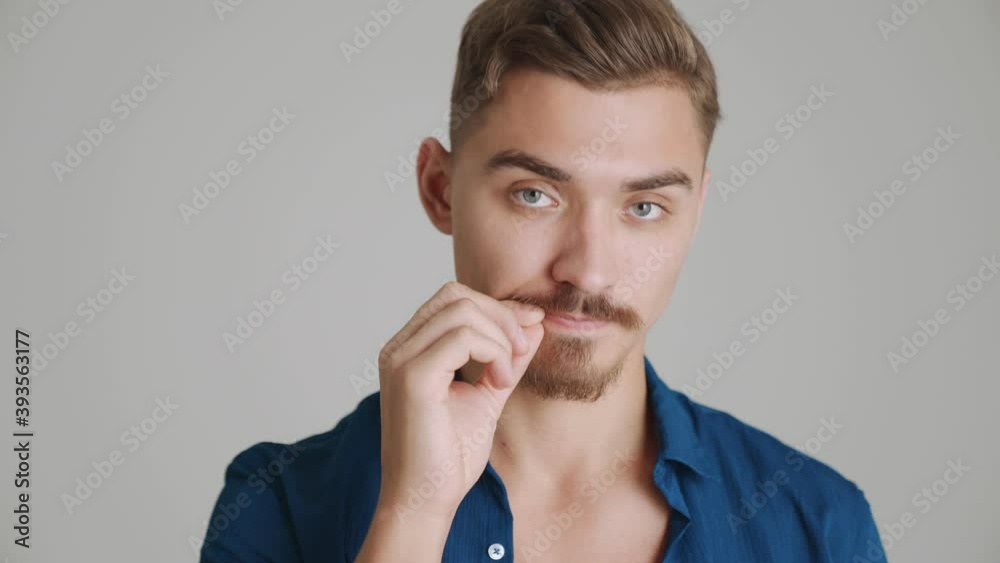 A close-up view of a serious man is showing his mouth closed standing isolated over gray background in studio A close-up view of a serious man is showing his mouth closed standing isolated over gray background in studio