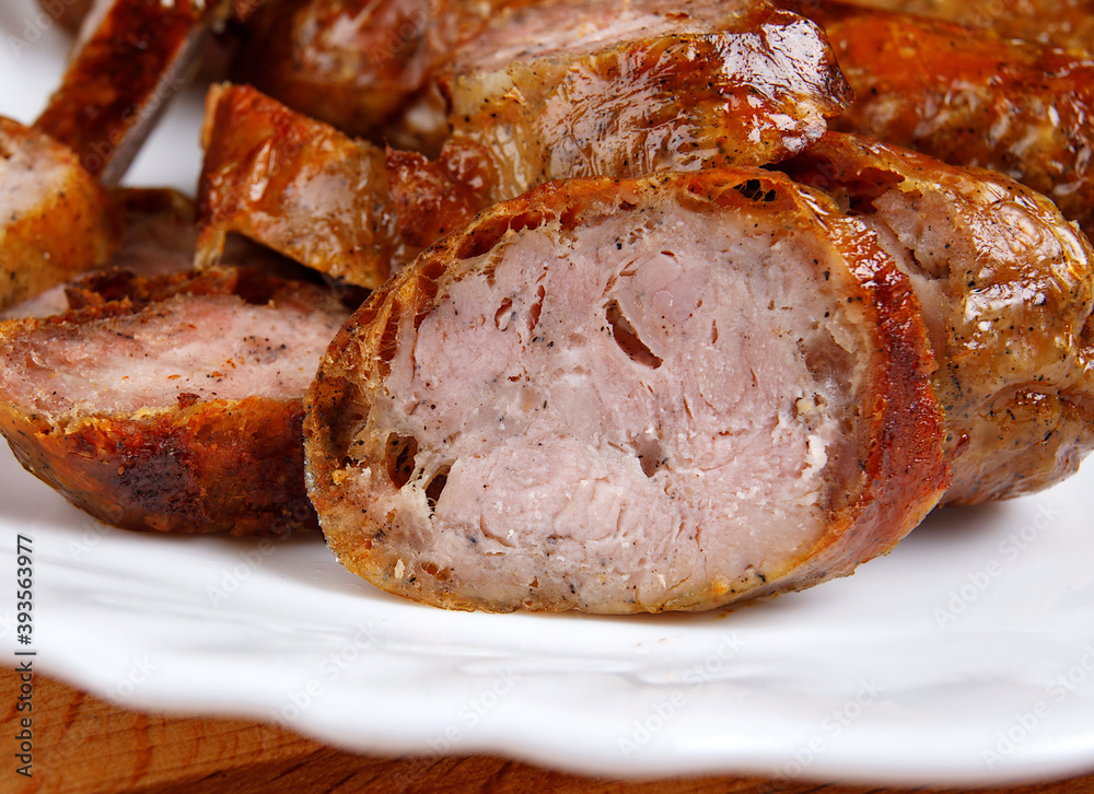 Pieces of homemade fried sausage lie on a white plate. Pieces of homemade fried sausage lie on a white plate.