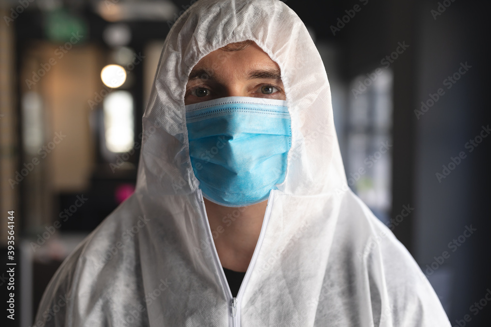 Portrait of male health worker wearing face mask and protective clothes at modern office