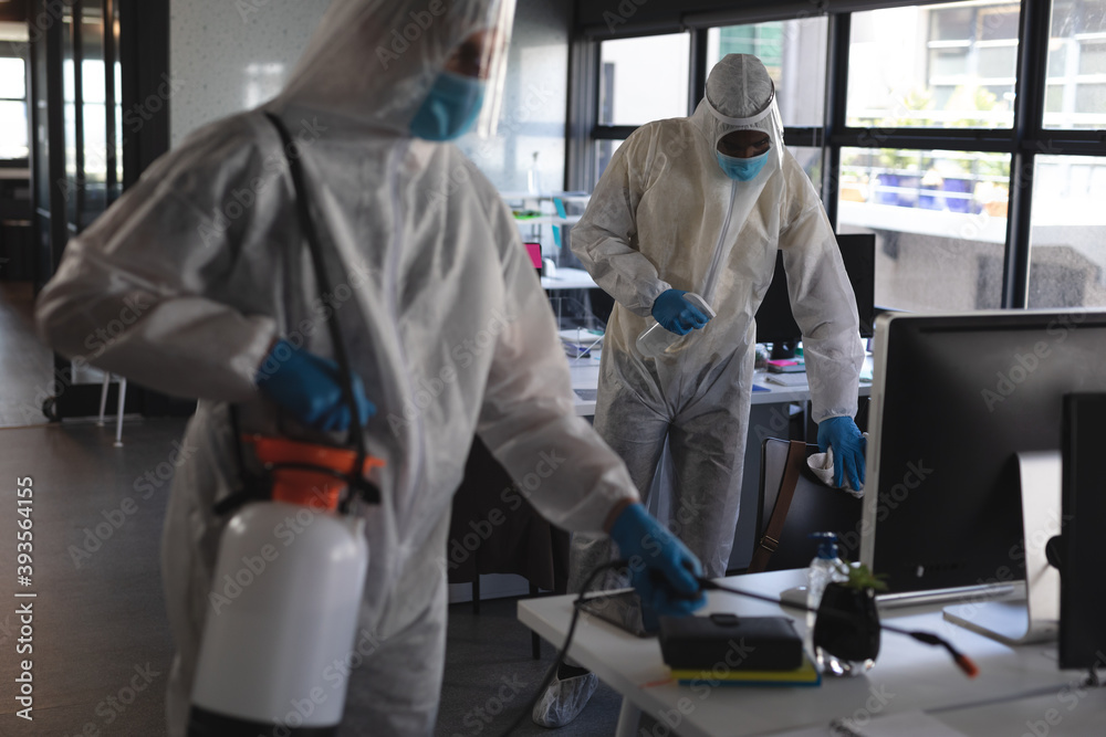 Team of health workers wearing protective clothes cleaning office using disinfectant Team of health workers wearing protective clothes cleaning office using disinfectant