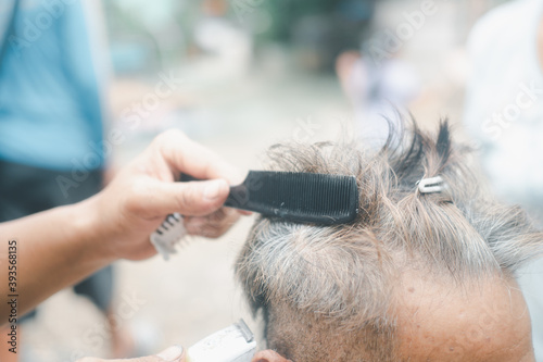 Hairdresser making stylish haircut for old man in home.