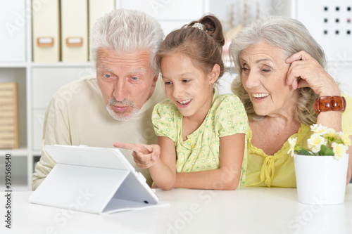 Portrait of grandparents with granddaughter using tablet