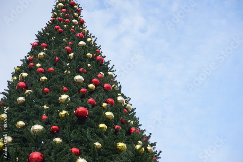 christmas tree with garlands of glowing and decorations, blue sky
