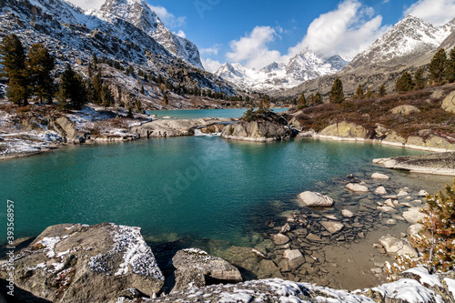 The rocky shore of the mountain lake is covered with snow