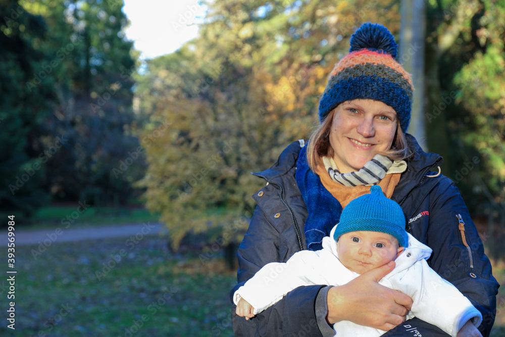 Portrait of a smiling mother with a baby boy son in the park in the winter Portrait of a smiling mother with a baby boy son in the park in the winter