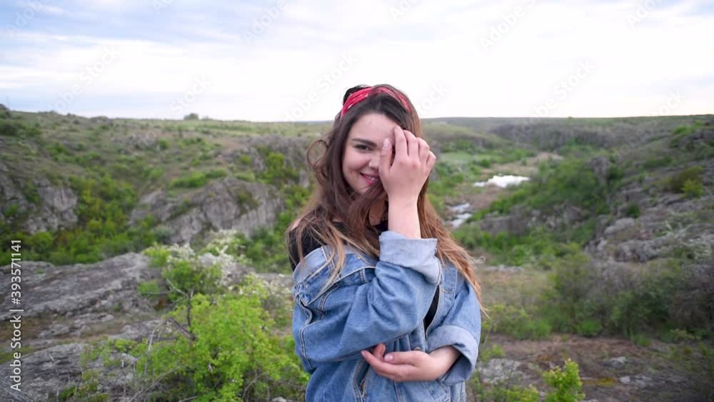 Portrait of the smiling pretty brunette girl in jeans jacket in the background of the canyon at dusk Portrait of the smiling pretty brunette girl in jeans jacket in the background of the canyon at dusk