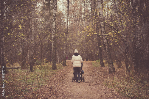 A girl with a stroller walks in the autumn forest