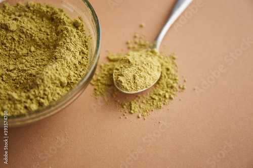 Henna mhendi colorant powder in a glass bowl and a wooden comb on a beige background top view. Ayurvedic hair care products. Natural care and hair coloring. photo