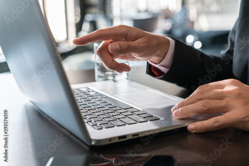 Office manager male hands typing on laptop keyboard, closeup. Businessman working with laptop, no face, male finger pointing no the computer screen, device on wooden office table, concept of work