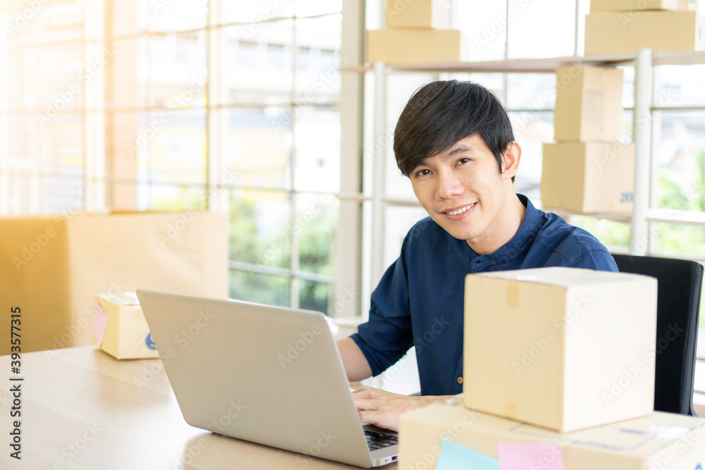 Young man starts small business (SME) by delivering products packed into boxes through a logistics system from home office, package delivery, online marketing, e-commerce concept. Young man starts small business (SME) by delivering products packed into boxes through a logistics system from home office, package delivery, online marketing, e-commerce concept.